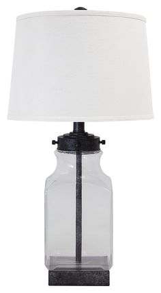 a clear glass lamp with a white shade on the base and a black metal frame