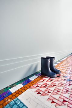 a pair of black rain boots sitting on top of a colorful floor next to a white wall