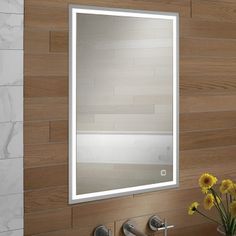 a bathroom sink with a mirror above it and flowers in the vase on the counter