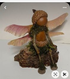 a figurine of a fairy sitting on top of a tree stump with wings