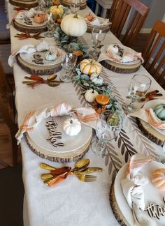 the table is set for thanksgiving dinner with pumpkins and gourds on it