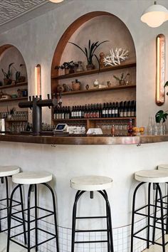 a bar with stools and shelves filled with bottles