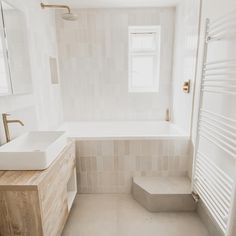 a bathroom with a sink, mirror and bathtub next to a wall mounted radiator