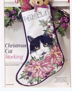 a cross stitch christmas stocking with a black and white cat