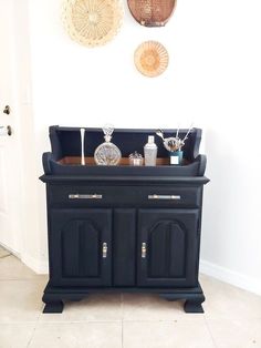 a black cabinet sitting in the corner of a room next to a wall with baskets on it