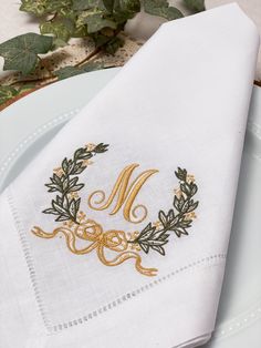 a white plate topped with a napkin covered in gold embroidered monogram