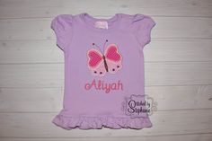 This is a listing for a made to order girls lavender short sleeved shirt in sizes 12 mo, 18 mo, 24 mo, 3T, 4T, 5T, 6, or 8. Shirts have puff sleeves and ruffles at the hem. A pink butterfly with purple hearts is machine embroidered onto the shirt with your child's name underneath in your choice of font. I can also leave the name off. All my shirts are prewashed in unscented detergent to prevent shrinking once the embroidery is added. When you place your order, please let me know what size, font, Cute Fitted Purple T-shirt, Heart Butterfly, Cat Birthday Party, Purple Hearts, Applique Shirts, Ruffle Shirt, Personalized Embroidered, Pink Butterfly, Embroidered Shirt