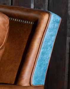 a brown leather chair with blue upholstering on the back and armrests