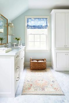 a white bathroom with blue walls and a rug on the floor in front of it