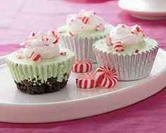 three cupcakes with white frosting and candy canes on a platter