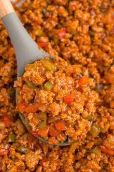 a wooden spoon full of chili and meat mixture in a pan with a spatula