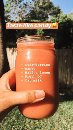 someone holding up a jar of orange colored drink in front of a fence with the words taste like candy on it