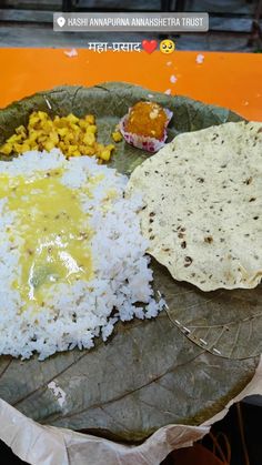 a plate filled with rice and other food on top of a leafy green plate