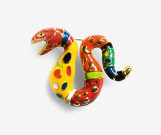 a colorful snake brooch sitting on top of a white surface