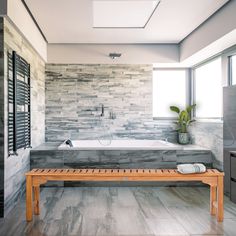 a bathroom with a wooden bench in front of the bathtub