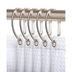 four metal hooks hang on the side of a white curtain with silver rings attached to it