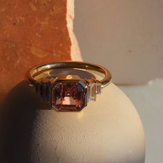 This peach beauty has an art deco feel and plenty of stackability. A 2.03ct unheated step cut pink sapphire from Madagascar is bezel set in the center and accompanied by four straight baguette cut diamonds. Complimentary resizing available for sizes 4 through 8; simply add a note with preferred size when checking out. Please note resizing this ring adds an extra 7-10 days for delivery. Diamond Baguette Ring, Peach Sapphire, Diamond Baguette, Baguette Diamond Rings, Baguette Ring, Ring Bezel, Step Cut, Baguette Cut Diamond, Original Jewelry