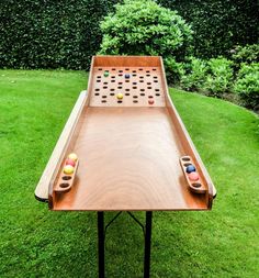 a wooden table with two game pieces on it in the middle of a grassy area