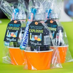 three orange cups filled with drinks on top of a green table covered in plastic bags