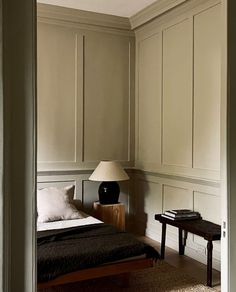 a bed sitting in the middle of a bedroom next to a table with a lamp on it