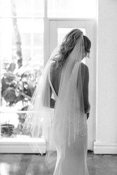 the back of a bride's dress as she stands in front of a window