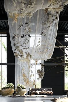 an open room with sheer curtains and flowers in vases on the floor next to windows