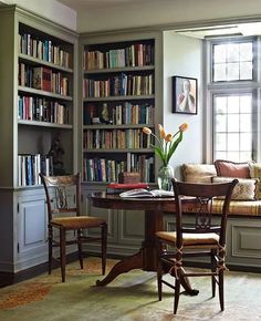 a living room filled with lots of furniture and bookshelves next to a window