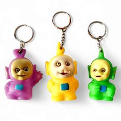 three plastic key chains with cartoon characters on them, one is yellow and the other is green