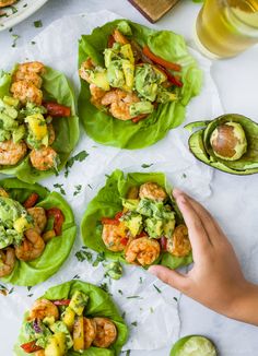 several lettuce cups with shrimp and avocado on them, one being held by a person