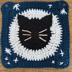 a crocheted square with a black and white cat's face on it