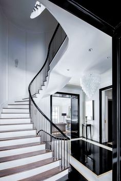 a black and white staircase with chandelier in the middle is featured in this photo