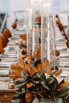 the table is set with candles and greenery for an elegant touch to the place setting