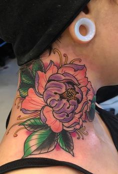 a woman with a tattoo on her neck and behind her ear is a pink flower