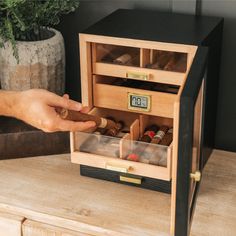 a person is opening an open drawer in a wooden box on top of a table