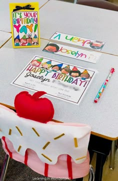 a table topped with an apple covered in frosting next to two books and pencils