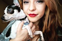 a woman is holding a small dog in her arms and posing for the camera with red lipstick