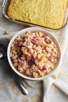 a white bowl filled with beans next to a casserole dish on a table