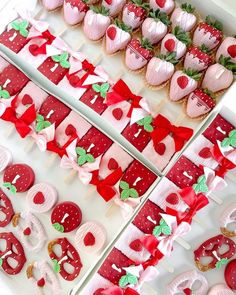 strawberry shortcakes are arranged in rows on trays with red bows and green leaves