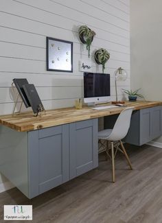 a desk with a computer on top of it in front of a wall mounted clock