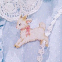 a small stuffed animal laying on top of a white lace doily next to a blue dress