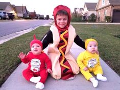 three children dressed up in costumes sitting on the sidewalk next to each other and one child wearing a hot dog costume