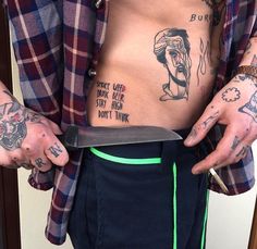 a man with tattoos on his stomach holding a knife