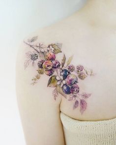 a woman's shoulder with flowers and leaves on her left side, which is covered in tattoos