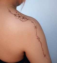 the back of a woman's shoulder with flowers and vines tattoo on her upper arm