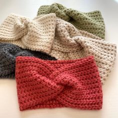 four knitted headbands on top of each other with a bow at the end