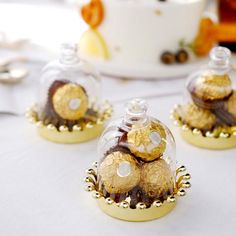 three glass bottles filled with gold and chocolate covered pastries on top of a white table cloth