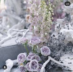 a bunch of flowers sitting on top of a table covered in white and purple stuff