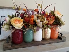 four mason jars with flowers in them are sitting on a wooden shelf next to a sign