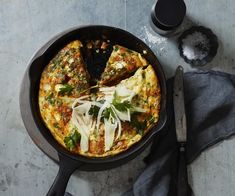 an omelet with cheese and greens in a skillet next to a knife