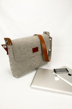 a bag sitting next to an apple laptop on top of a white table with a cell phone